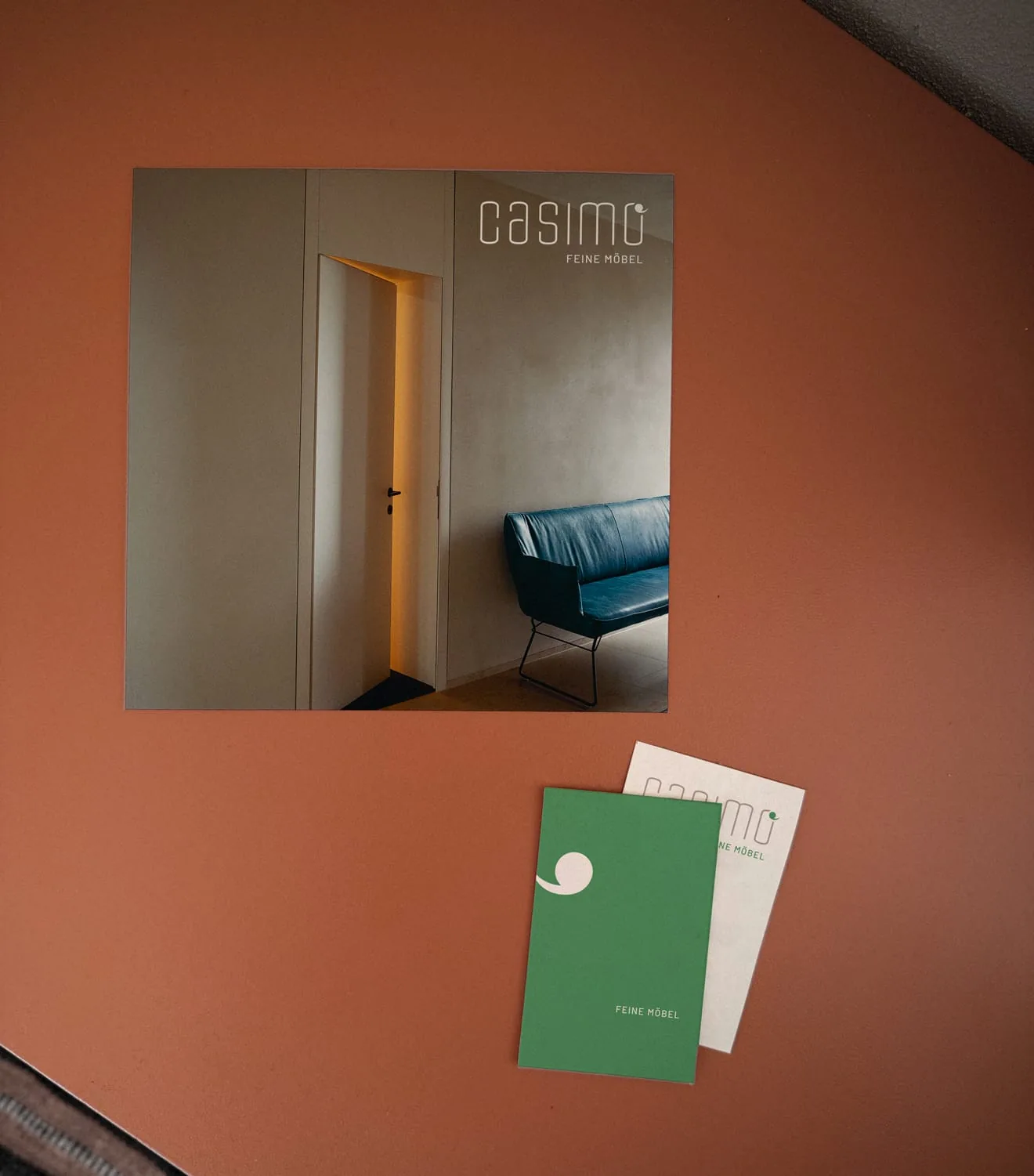 casimo "Casimo" flyer and two matching business cards on a rust-colored bench.