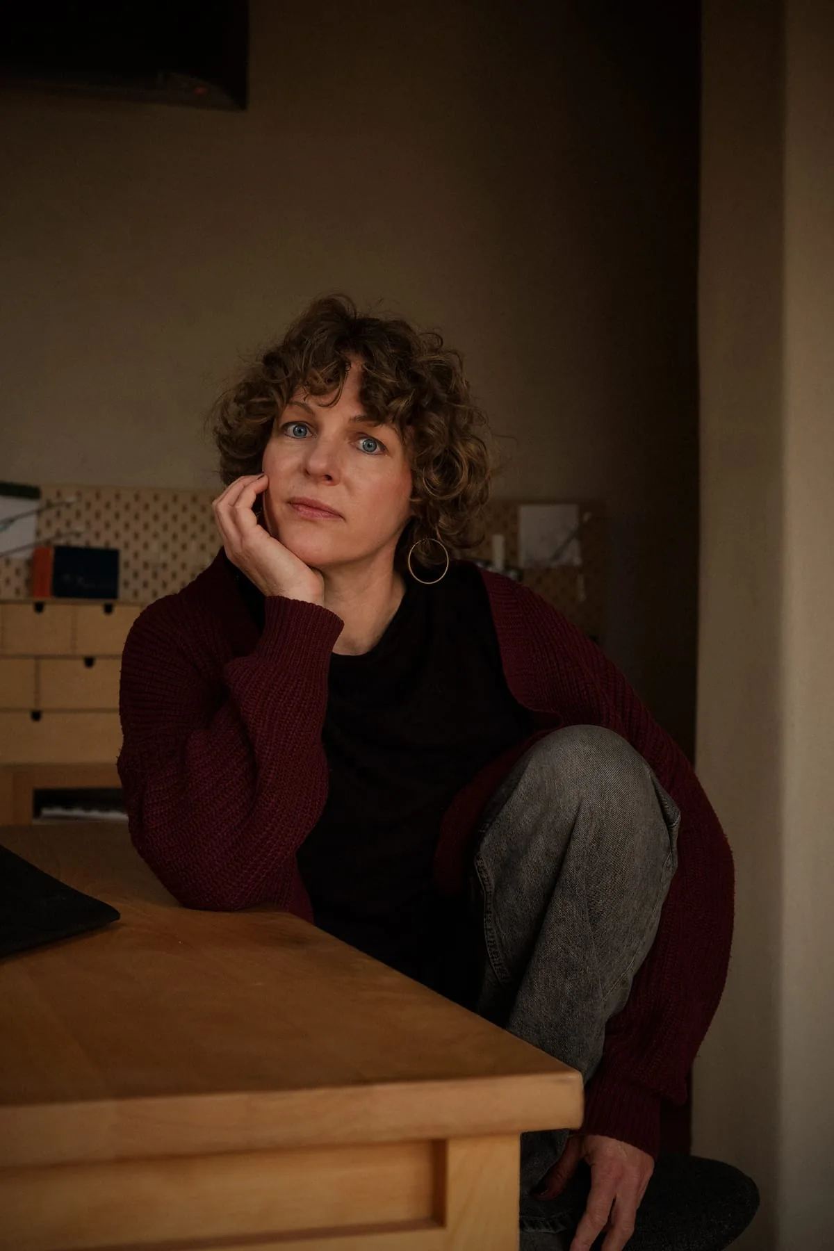 Ursula Hechenberger-Schwaerzler: a woman with curly hair, in a dark room, next to a wooden desk.